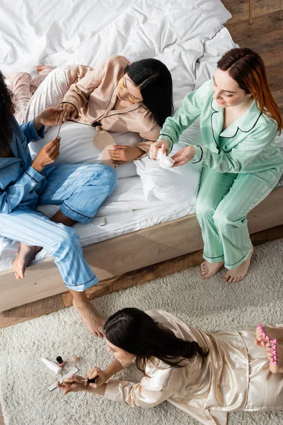 High angle view of african american woman doing manicure to asian friend during slumber party — Stock Photo