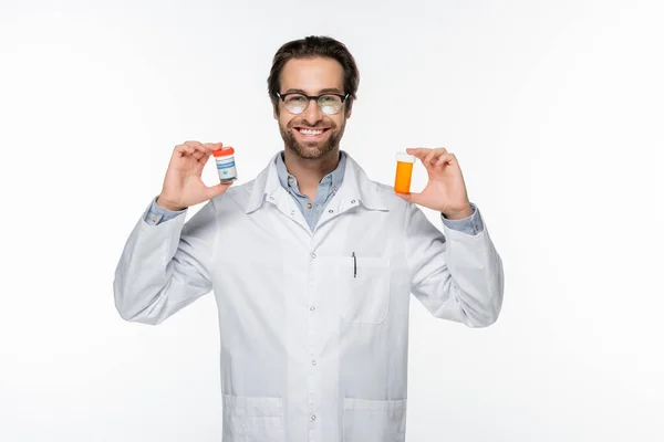 Sonriente médico mostrando recipientes con cannabis medicinal aislado en blanco - foto de stock