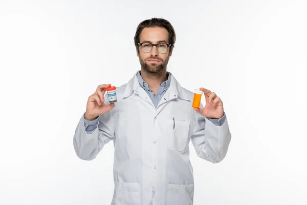 Doctor in eyeglasses holding containers with medical cannabis isolated on white — Stock Photo