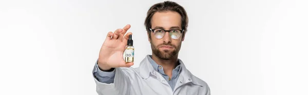 Doctor in eyeglasses showing bottle of cannabis oil isolated on white, banner — Stock Photo