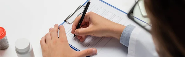 Cropped view of blurred doctor writing prescription near containers with treatment, medical cannabis concept, banner — Stock Photo