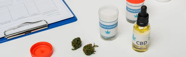 Récipients avec huile et cannabis médical sec près du presse-papiers sur bureau blanc, bannière — Photo de stock