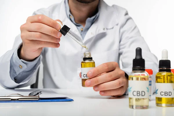 Teilansicht des Arztes mit Tropfer und Fläschchen mit cbd-Öl isoliert auf weiß — Stockfoto