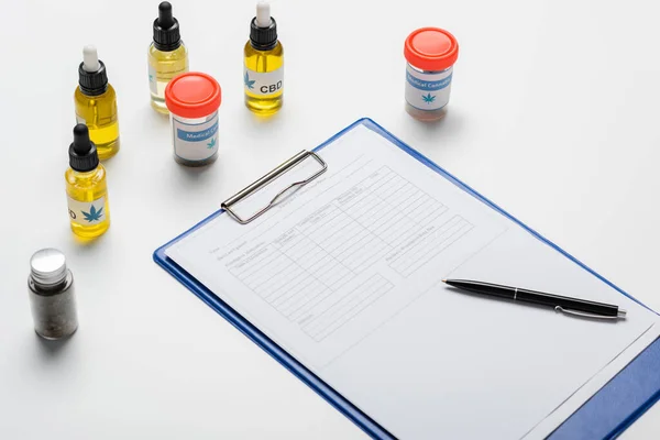 Flaschen und Behälter mit medizinischem Cannabis in Rezeptnähe auf weißem Schreibtisch — Stockfoto