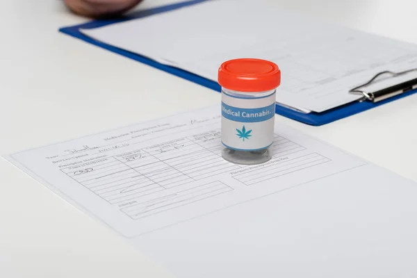 Container with dry medical hemp near medical cards on white desk — Stock Photo