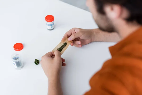 Teilsicht auf kranken Mann, der Joint mit medizinischem Cannabis zu Hause herstellt — Stockfoto