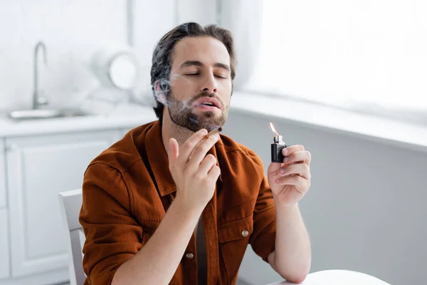 Man closing eyes while holding joint of medical cannabis and lighter — Stock Photo