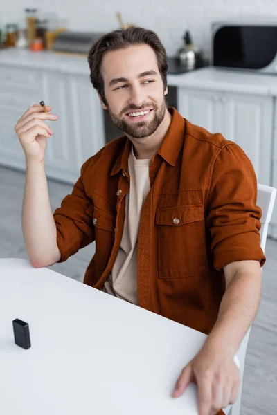 Positive man holding joint of medical cannabis near lighter in kitchen — Stock Photo