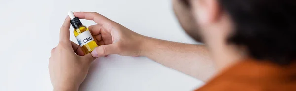 Vue recadrée de la bouteille d'huile de cbd dans les mains de l'homme flou, bannière — Photo de stock