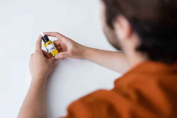 Vue recadrée d'un homme flou tenant une bouteille d'huile de cbd — Photo de stock