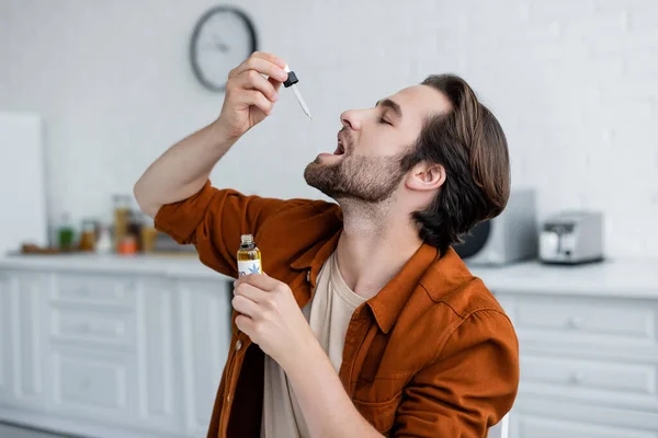 Vue latérale de l'homme prenant de l'huile de cbd à la maison — Photo de stock