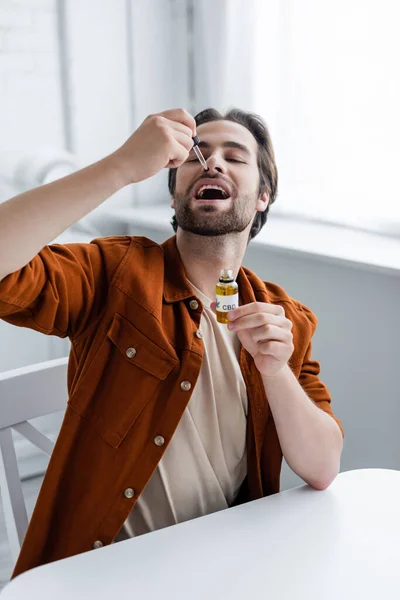 Man holding bottle and pipette while taking cbd oil — Stock Photo