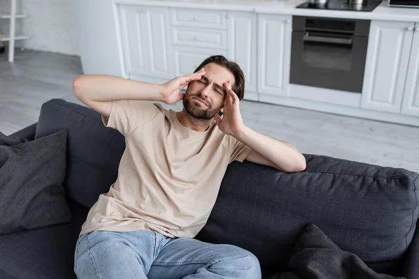 Hombre cogido de la mano cerca de la cabeza mientras sufre de dolor de cabeza - foto de stock