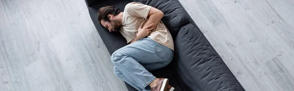 Vista superior del hombre que sufre de dolor de estómago en el sofá, bandera - foto de stock