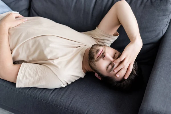 Kranker Mann mit geschlossenen Augen zu Hause auf Couch liegend — Stockfoto
