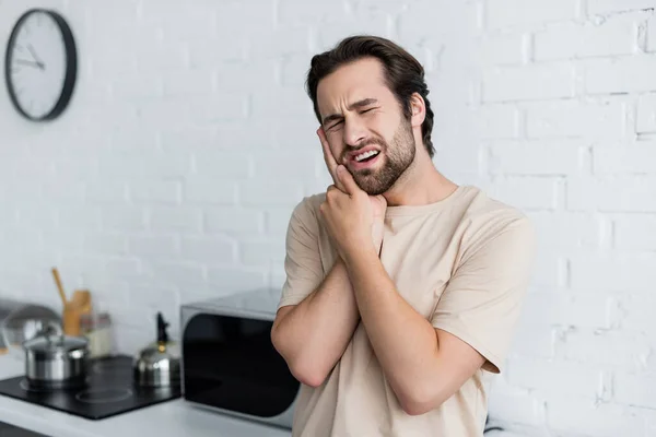 Человек, страдающий зубной болью при прикосновении к щеке — стоковое фото