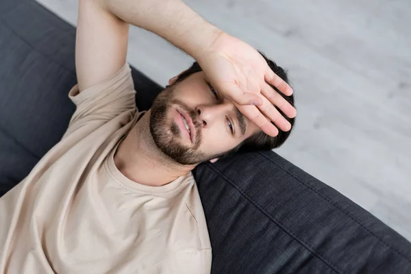 Vista de ángulo alto del hombre enfermo que sufre de dolor de cabeza - foto de stock