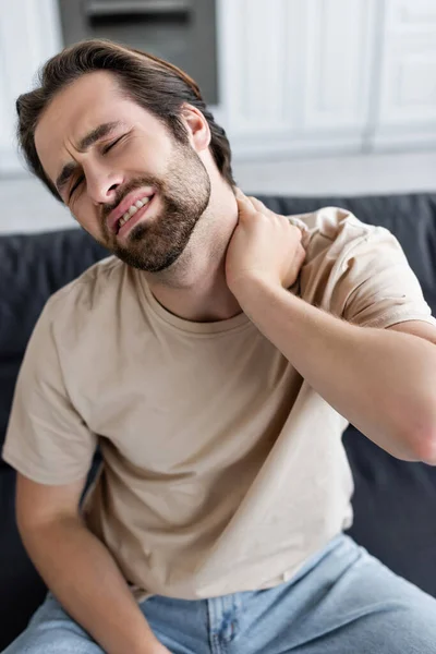 Tired man touching painful neck at home — Stock Photo