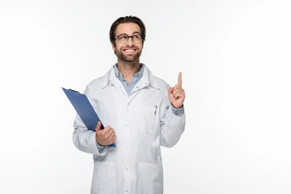 Médico sorridente tendo ideia e segurando prancheta isolada em branco — Fotografia de Stock