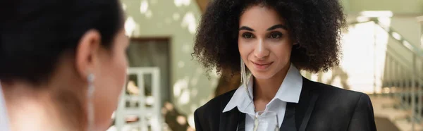 Afroamerikanisch lesbische Frau im Anzug steht neben verschwommener Freundin während der Hochzeit, Banner — Stockfoto