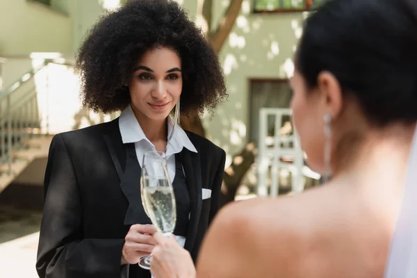 Afroamerikanisch lesbische Frau prostet Champagner mit verschwommener Freundin bei Hochzeit im Freien zu — Stockfoto