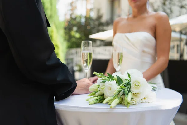 Vista cortada de mulher lésbica de terno perto do buquê de casamento, champanhe e namorada ao ar livre — Fotografia de Stock