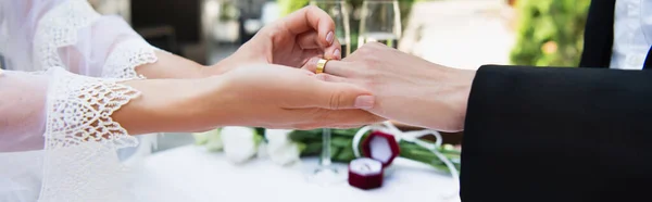Vista recortada de la mujer lesbiana que usa el anillo en el dedo de la novia durante la boda, bandera - foto de stock