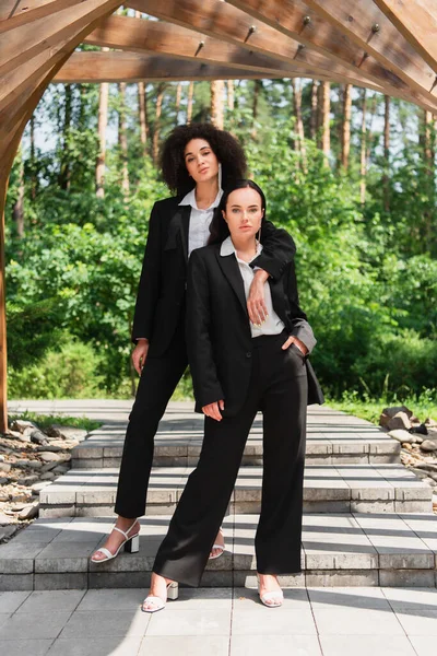 African american lesbian woman hugging girlfriend in suit outdoors — Stock Photo