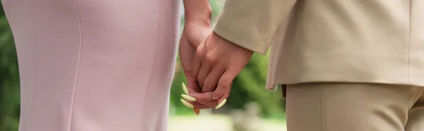 Cropped view of lesbian couple in dress and formal wear holding hands, banner — Stock Photo