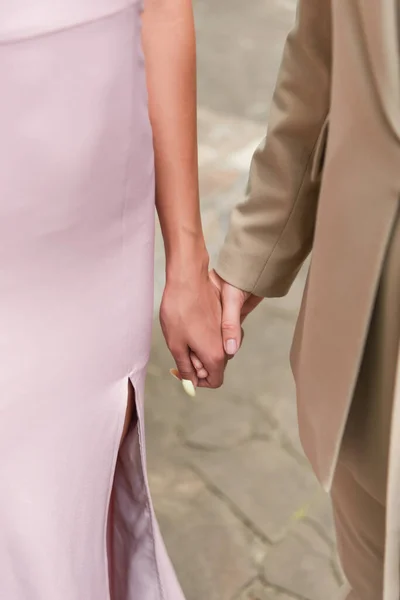 Vista ritagliata della coppia dello stesso sesso in abito e vestito che si tiene per mano all'aperto — Foto stock