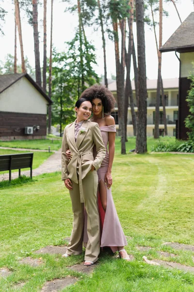 Smiling african american woman hugging girlfriend in suit outdoors — Stock Photo