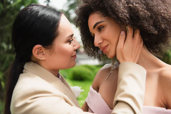 Young woman in formal wear touching african american girlfriend outdoors — Stock Photo