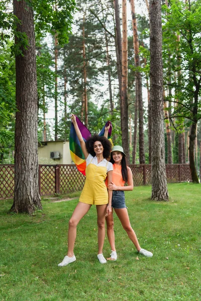 Веселі міжрасові жінки тримають lgbt прапор в парку — стокове фото