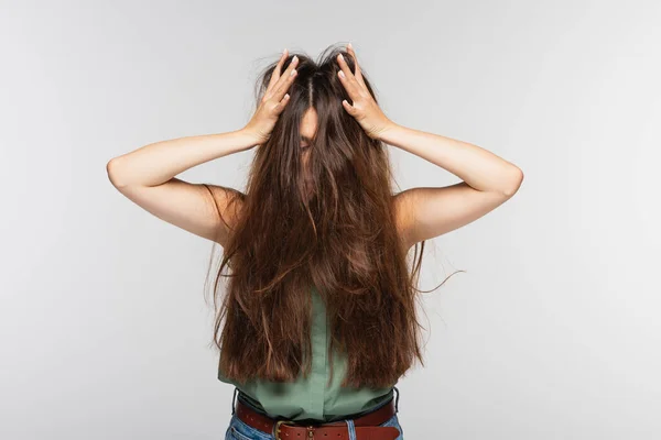 Молода жінка регулює заплутане довге волосся ізольоване на сірому — стокове фото