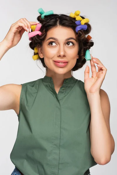 Souriant jeune femme ajustement coloré boucleur de cheveux isolé sur gris — Photo de stock