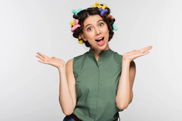 Excitée jeune femme avec des bigoudis colorés gesticulant isolé sur gris — Photo de stock