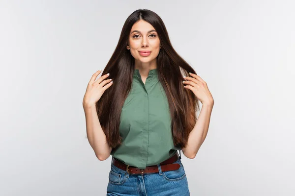 Allegra giovane donna dai capelli lucidi che guarda la macchina fotografica e sorride isolata sul grigio — Foto stock