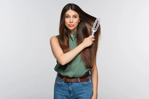 Bella giovane donna spazzolatura capelli lunghi isolati su grigio — Foto stock