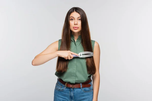 Brunette jeune femme brossage cheveux brillants isolés sur gris — Photo de stock