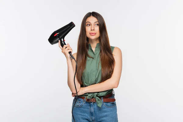 Jeune femme aux cheveux brillants tenant sèche-cheveux isolé sur gris — Photo de stock