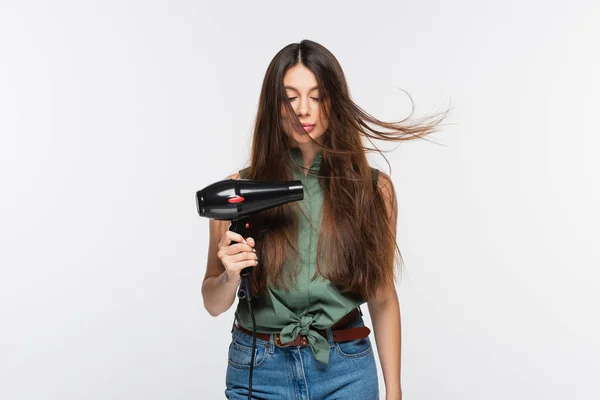 Jeune femme aux cheveux brillants utilisant sèche-cheveux isolé sur gris — Photo de stock
