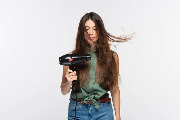 Giovane donna con capelli lucidi utilizzando asciugacapelli isolato su grigio — Foto stock