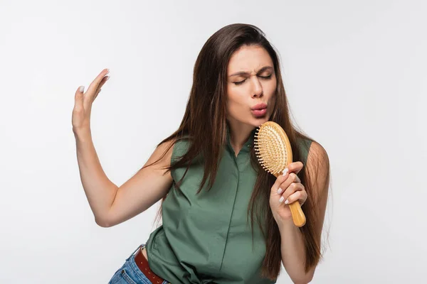 Молода жінка з блискучим волоссям співає в щітці для волосся ізольована на сірому — стокове фото