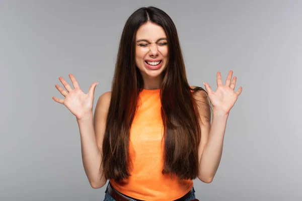 Cheerful young woman with closed eyes gesturing isolated on grey — Stock Photo