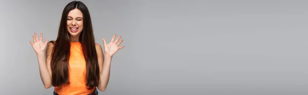 Cheerful young woman with closed eyes gesturing isolated on grey, banner — Stock Photo