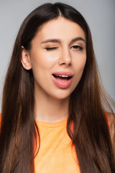 Flirty young woman winking eye isolated on grey — Stock Photo