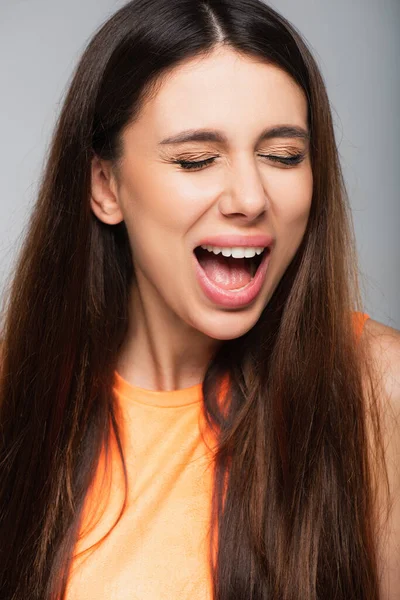 Young woman with closed eyes screaming isolated on grey — Stock Photo