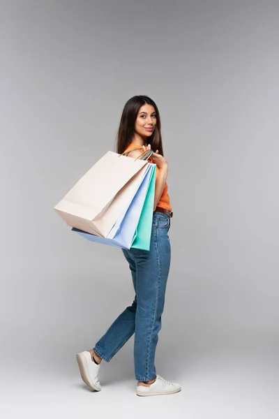 Junge Frau hält Einkaufstüten in voller Länge auf grau — Stockfoto