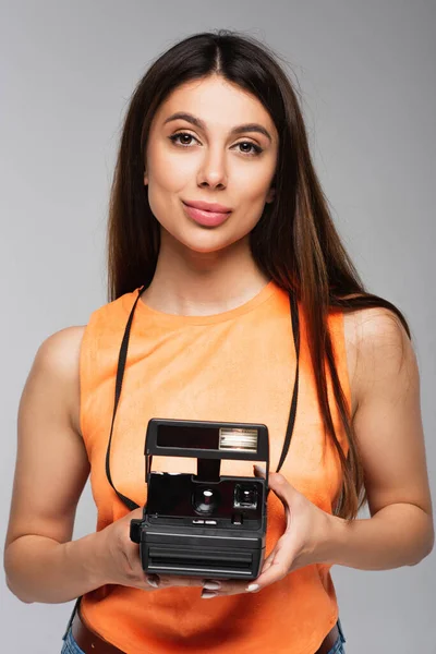 Young woman holding vintage camera isolated on grey — Stock Photo