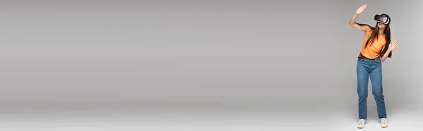 Intera lunghezza della giovane donna in auricolare vr su grigio, banner — Foto stock
